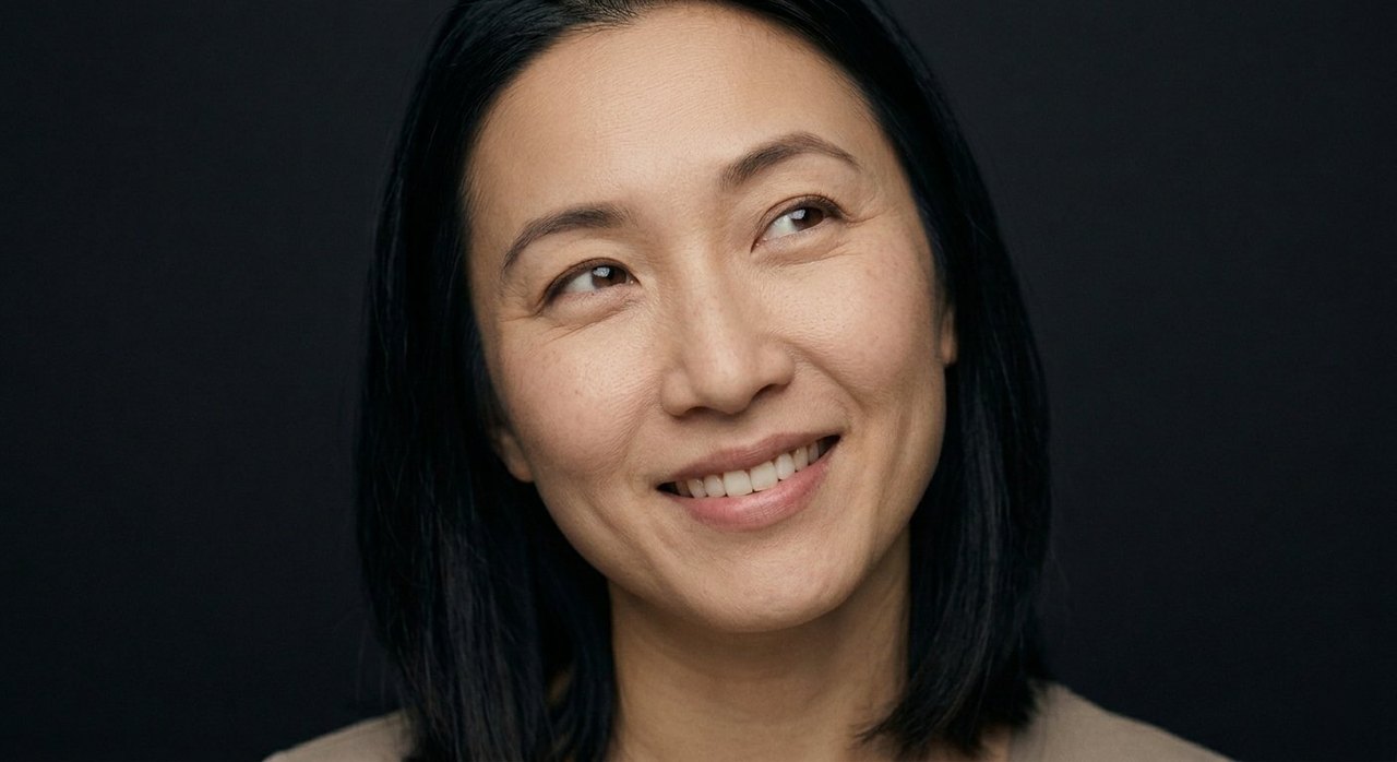 A woman's face showing cheerfulness: a warm cheerful smile and bright, friendly eyes turned aside.
