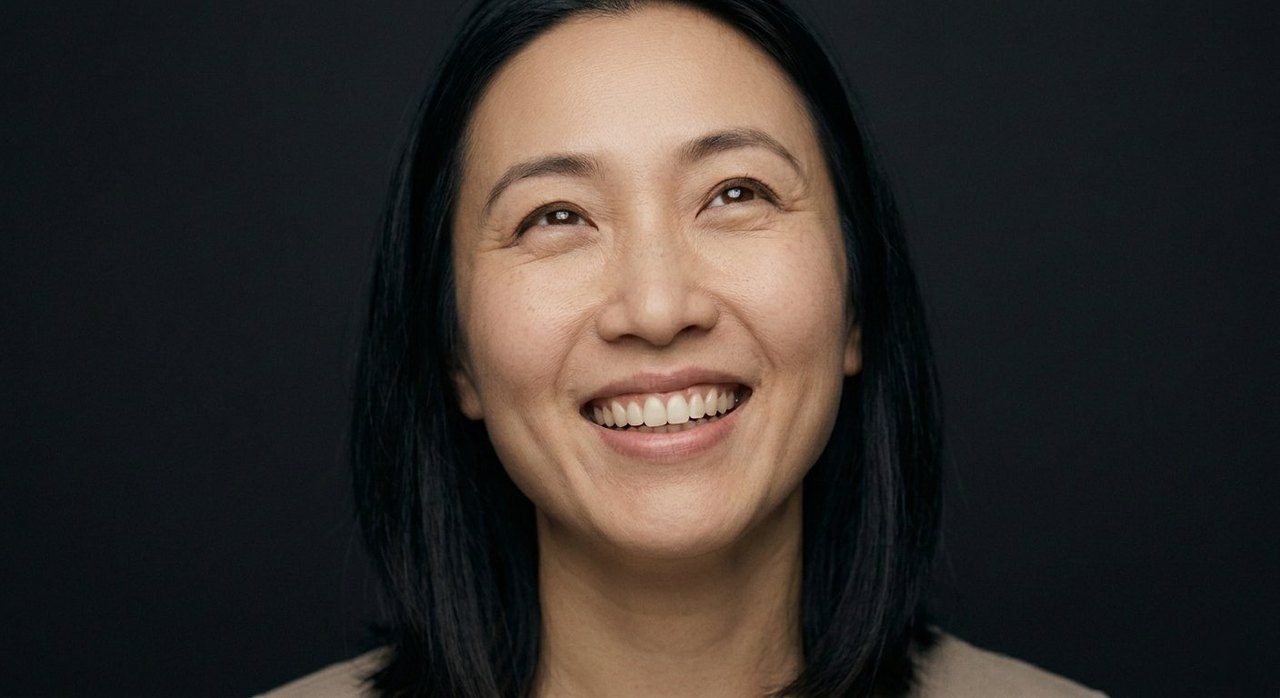 A woman's face showing elation: a wide toothy smile, raised cheeks, gaze lifted upward.