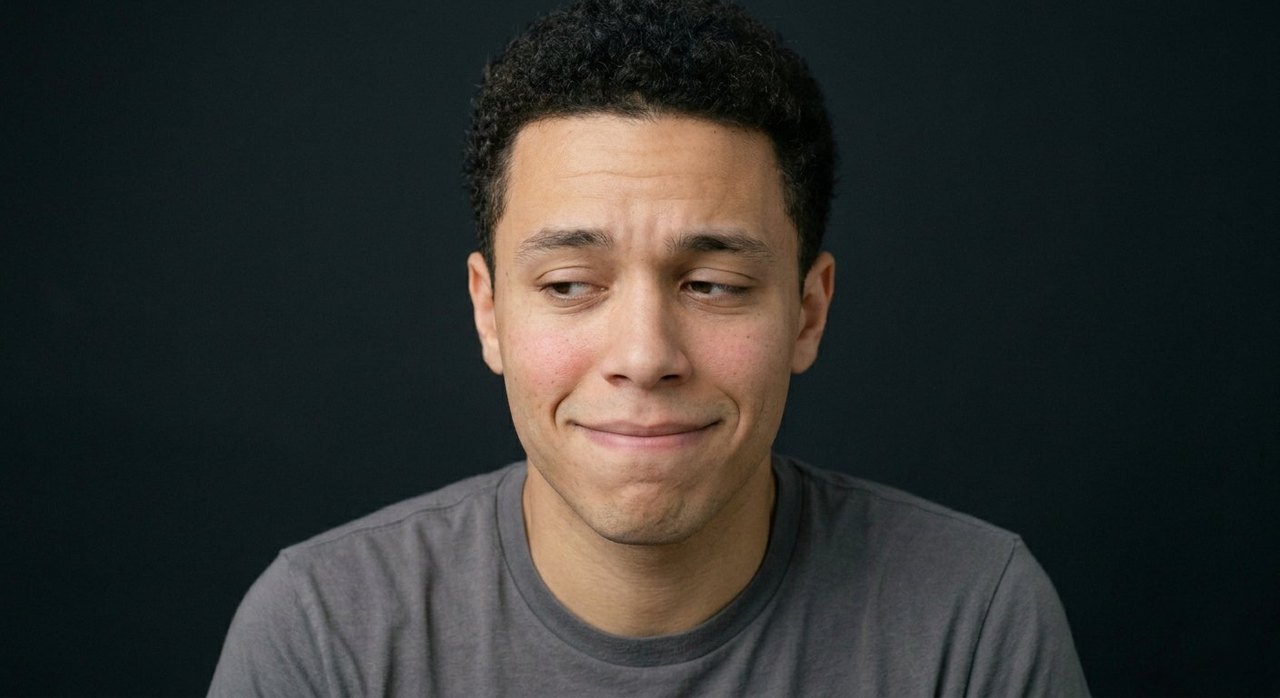 A man's face showing embarrassment: red flushed cheeks, watery eyes, an awkward grimace.