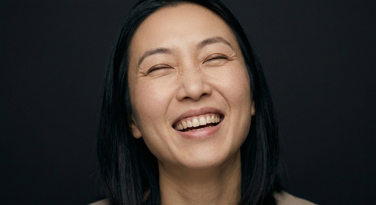 A woman's face showing euphoria: an open laugh, crinkled eyes, head tilted back slightly.