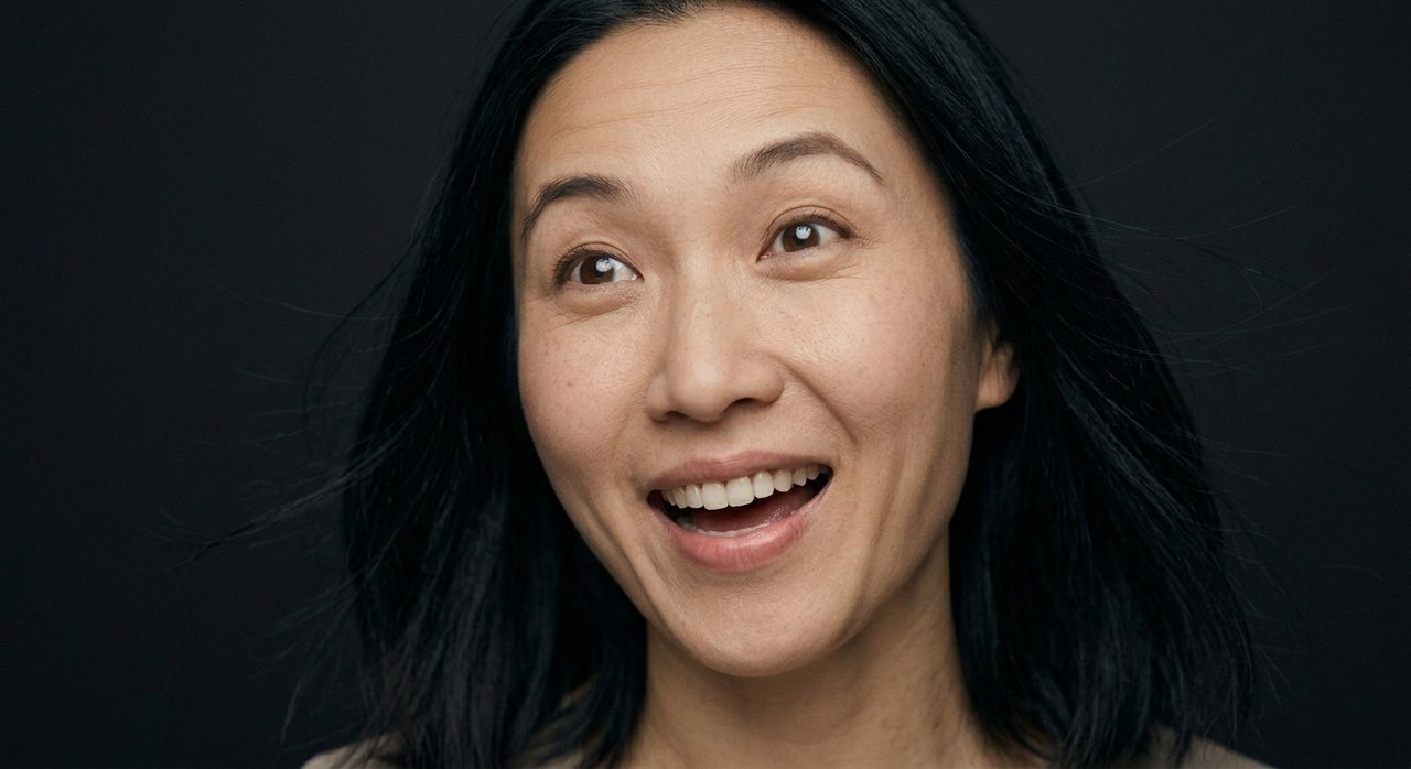 A woman's face showing exhilaration: wide bright eyes, open mouth, loose windswept hair.