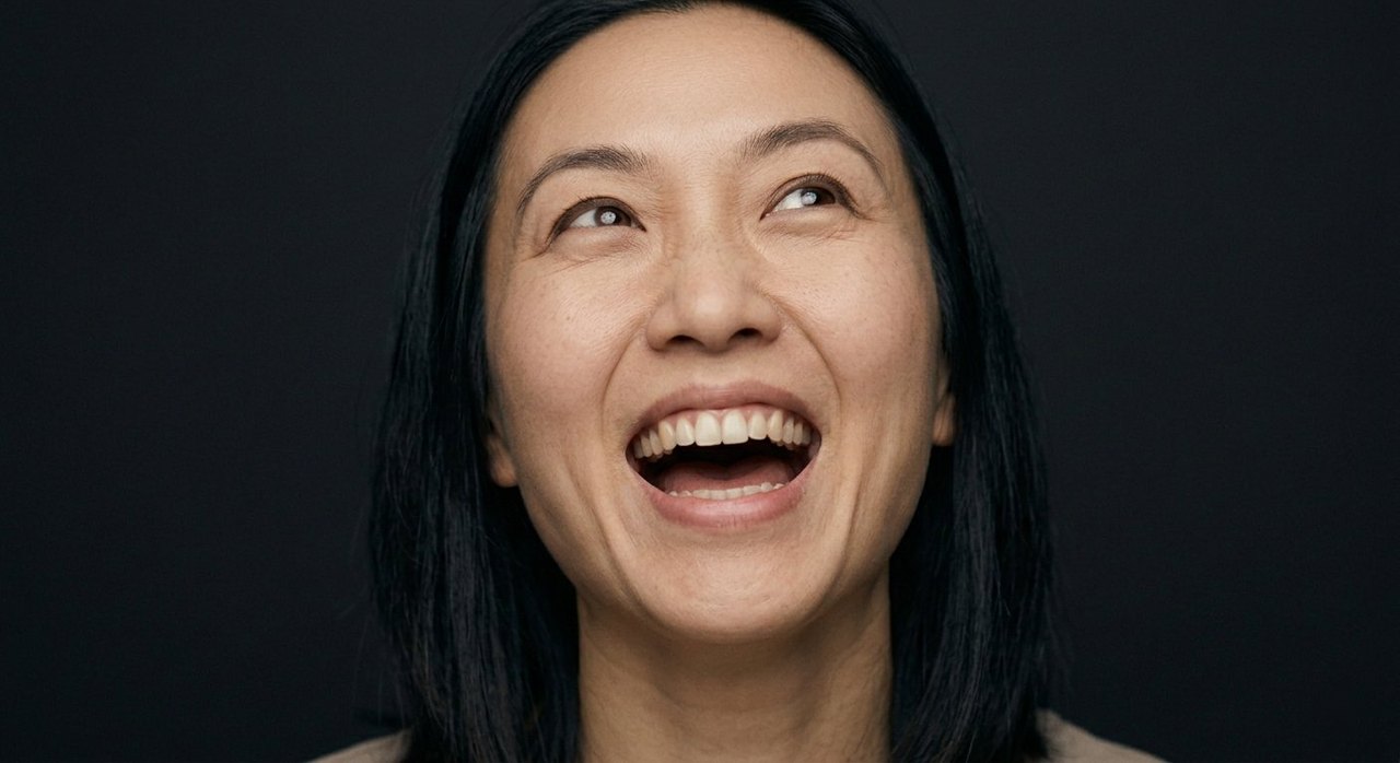 A woman's face showing exultation: an open-mouthed elated laugh and eyes raised in triumph.