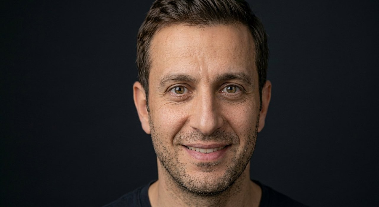 A man's face showing fervor: an eager smile and bright intense warm eyes.