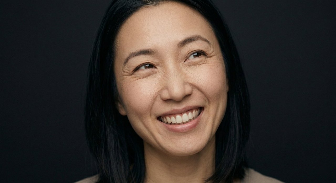 A woman's face showing festivity: a big bright smile, head turned, eyes alight with celebration.