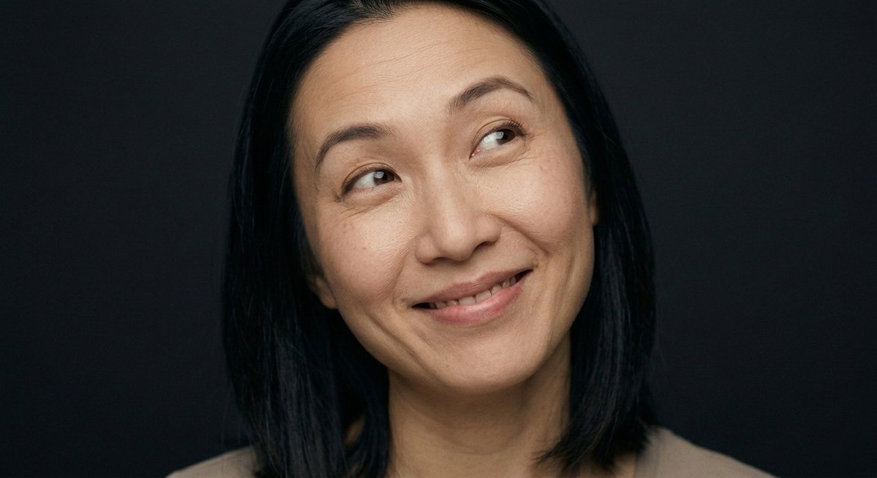 A woman's face showing giddiness: a giddy sidelong smile, lips parted, eyes bright and dizzy.