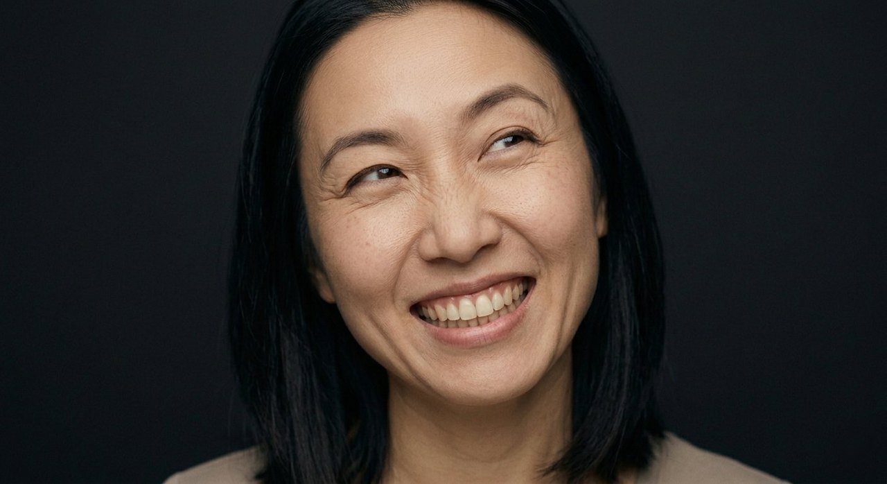 A woman's face showing glee: a wide delighted grin and bright, shining eyes.