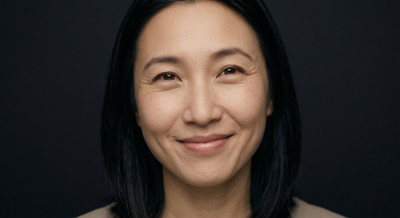 A woman's face showing happiness: a warm genuine smile and soft, crinkled, content eyes.