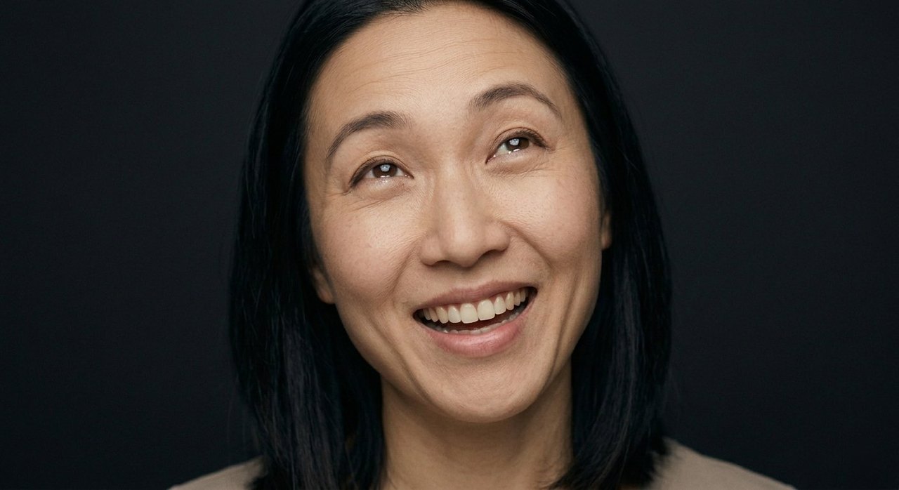 A woman's face showing jubilation: a broad open smile, teeth showing, gaze turned upward.