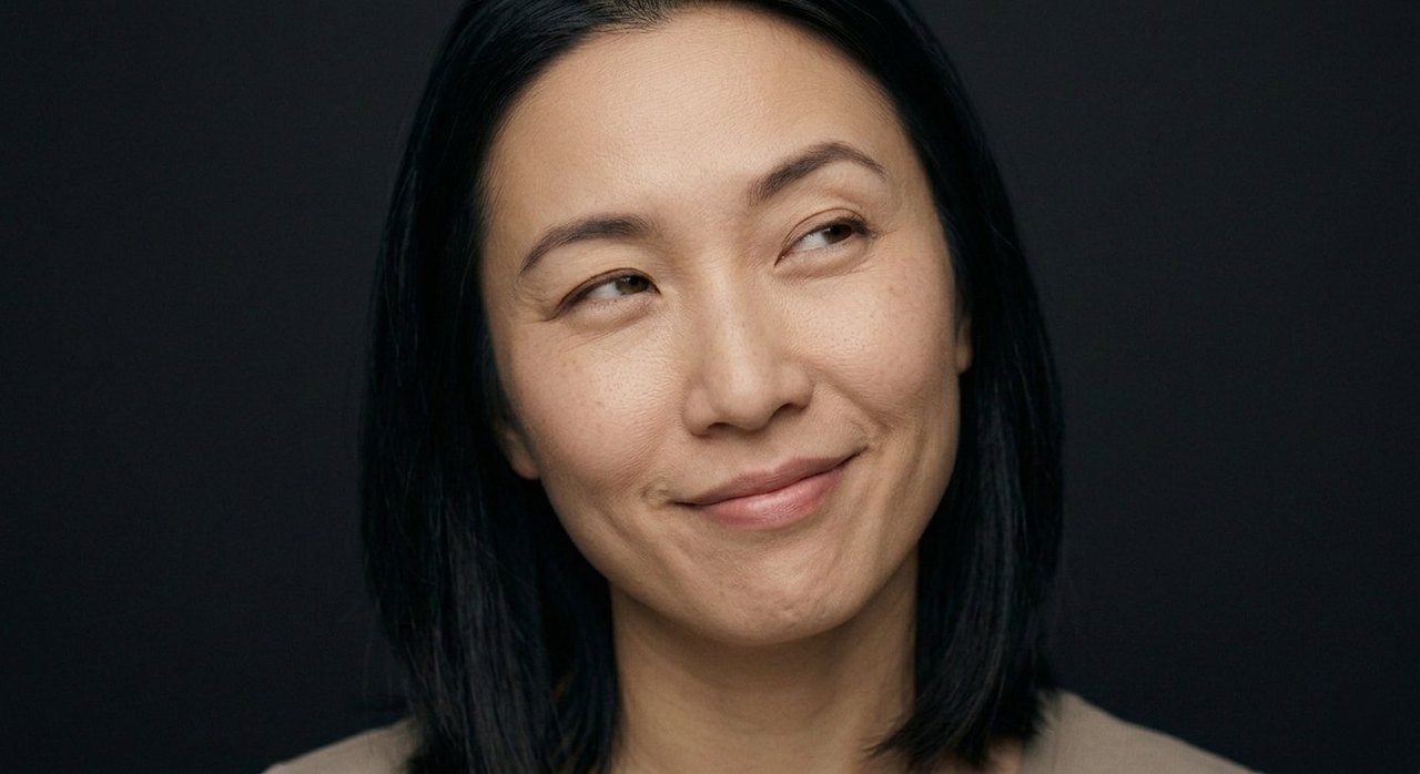 A woman's face showing mischief: a sly closed smile, eyes glancing sideways, knowing look.