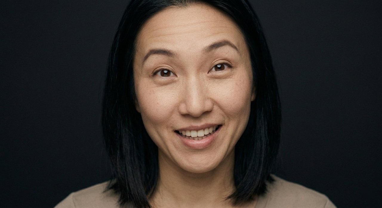 A woman's face showing playfulness: a cheeky playful grin and bright, teasing, lively eyes.