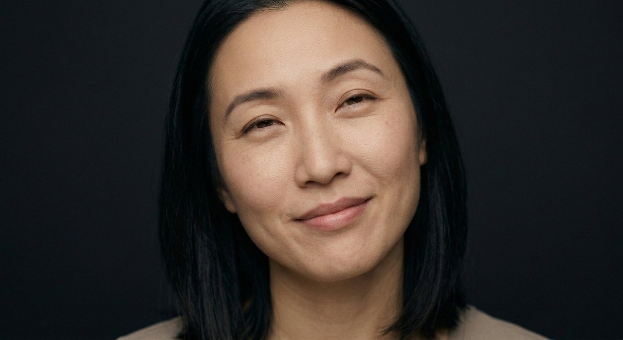 A woman's face showing pleasure: a soft pleased smile and relaxed, contented eyes.