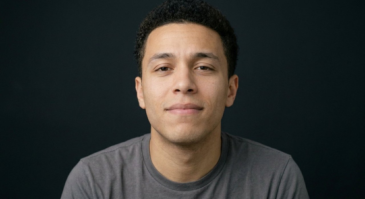 A man's face showing pride: a faint warm smile, lifted chin, calm gaze.
