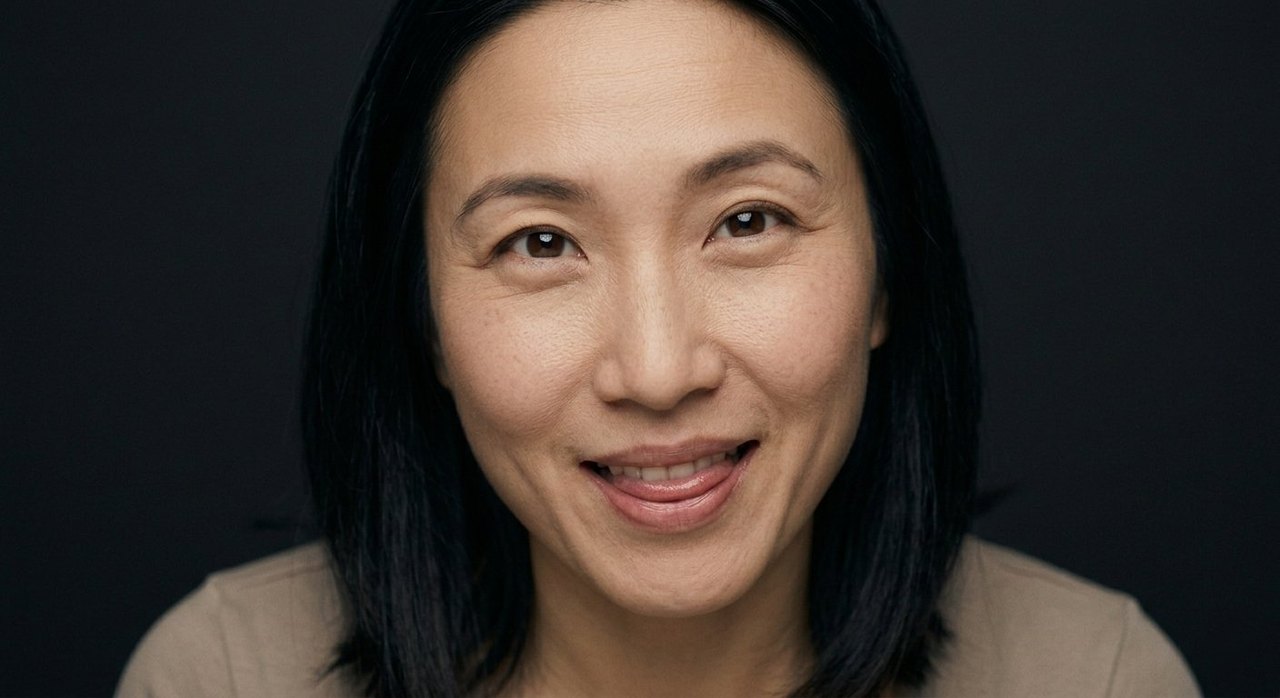 A woman's face showing relish: a savouring half-smile, lips parted, eyes warm with enjoyment.