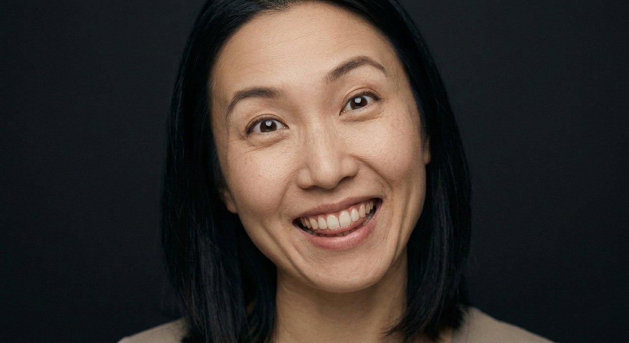 A woman's face showing silliness: a wide cheeky grin, bright eyes, teeth showing.
